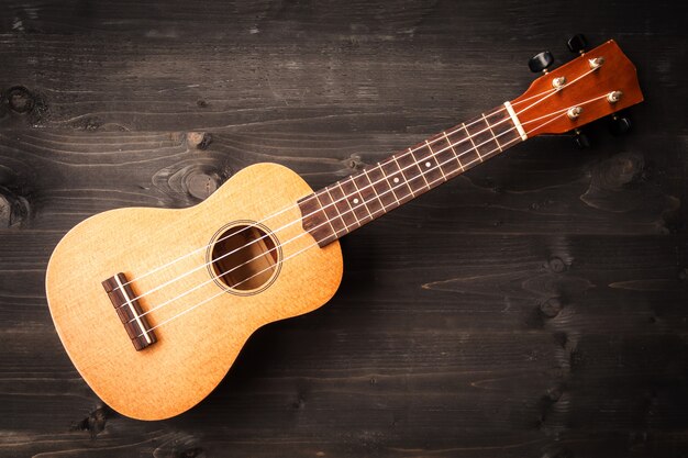 Ukulele auf schwarzem Hintergrund aus Holz. Akustisches Musikinstrument. Ansicht von oben.