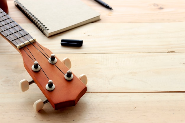 Foto ukulele e livro de nota em madeira