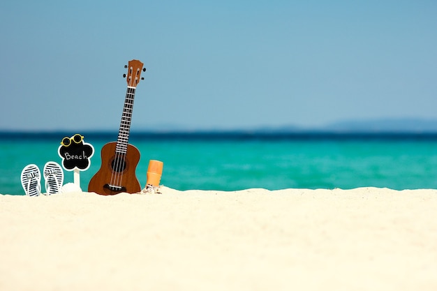 Ukulele na areia à beira-mar no verão perto da praia