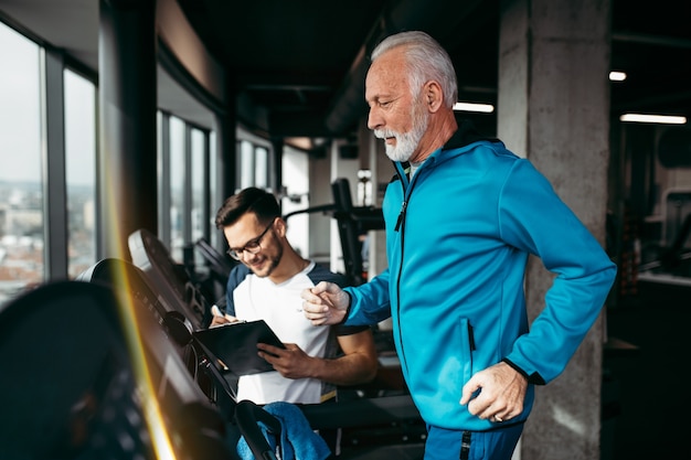 Último homem exercitando-se na academia com seu personal trainer.