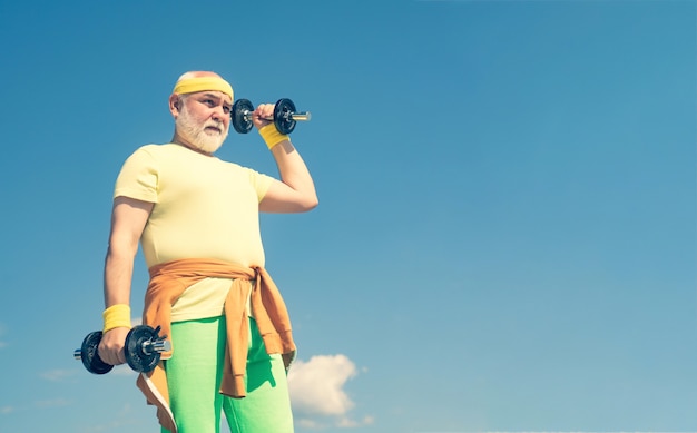 Último homem na academia de ginástica estar em movimento, velho segurando suas mãos na frente dele enquanto levanta halteres ...