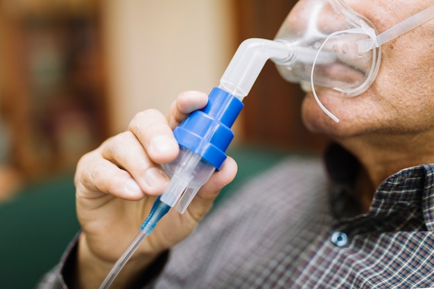 Último homem usando equipamento médico para inalação com máscara respiratória, nebulizador