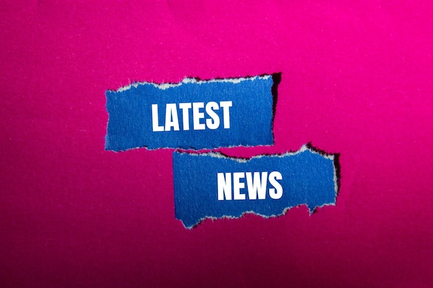 Último mensaje de noticias escrito en pedazos de papel azul rasgados con fondo rosa Símbolo conceptual de últimas noticias Espacio de copia