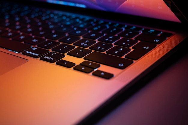 Foto ultrabook moderno en la mesa con pantalla medio abierta en luces de neón teclado negro con luz de fondo