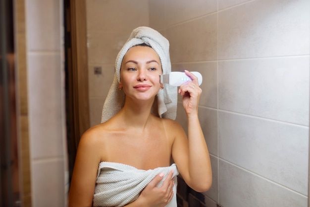 Ultraschallwäscher zur Reinigung der Gesichtshaut. Mädchen im Badezimmer kümmert sich um ihr Gesicht.