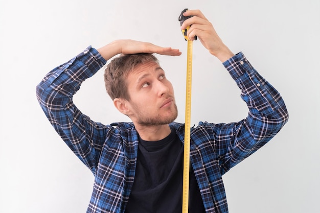 Foto um adolescente adulto simples do sexo masculino com uma fita de rolo mede a altura contra a parede