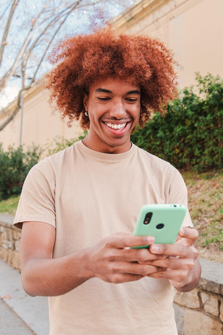 Foto um adolescente afro-americano usando um celular para enviar mensagens engraçadas isolado jovem feliz