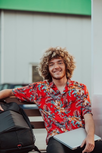 Um adolescente afro usa um laptop para uma reunião online enquanto está sentado em um banco de parque. foto de alta qualidade