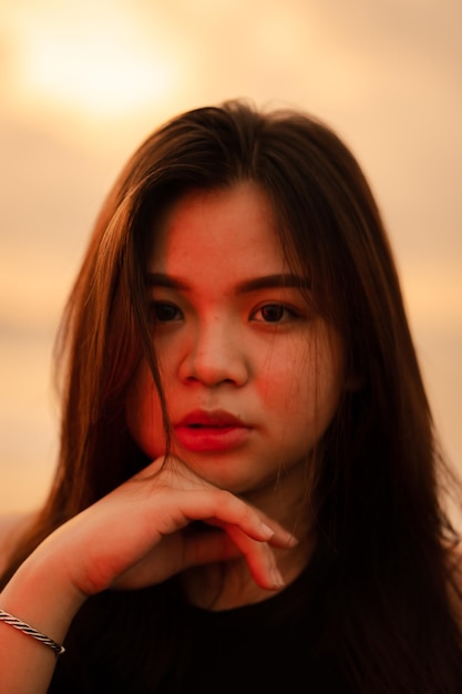 Um adolescente asiático relaxando na praia vestindo roupas pretas e posando lindamente