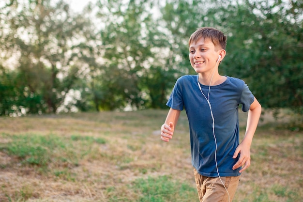 Um adolescente corre na natureza com fones de ouvido ouvindo música