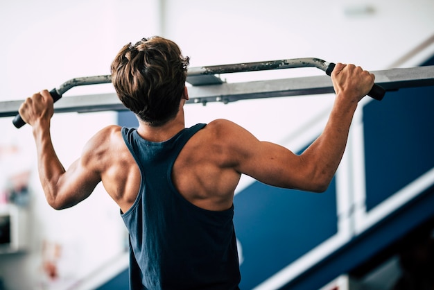 Um adolescente trabalhando sozinho na academia está treinando e fazendo exercícios de elevação - foto em preto e branco - homem forte e estilo de vida alegre