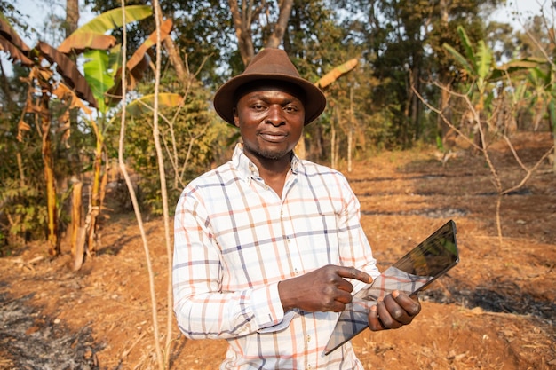 Um agricultor africano em seu campo com um tablet na mão tecnologia na agricultura na África