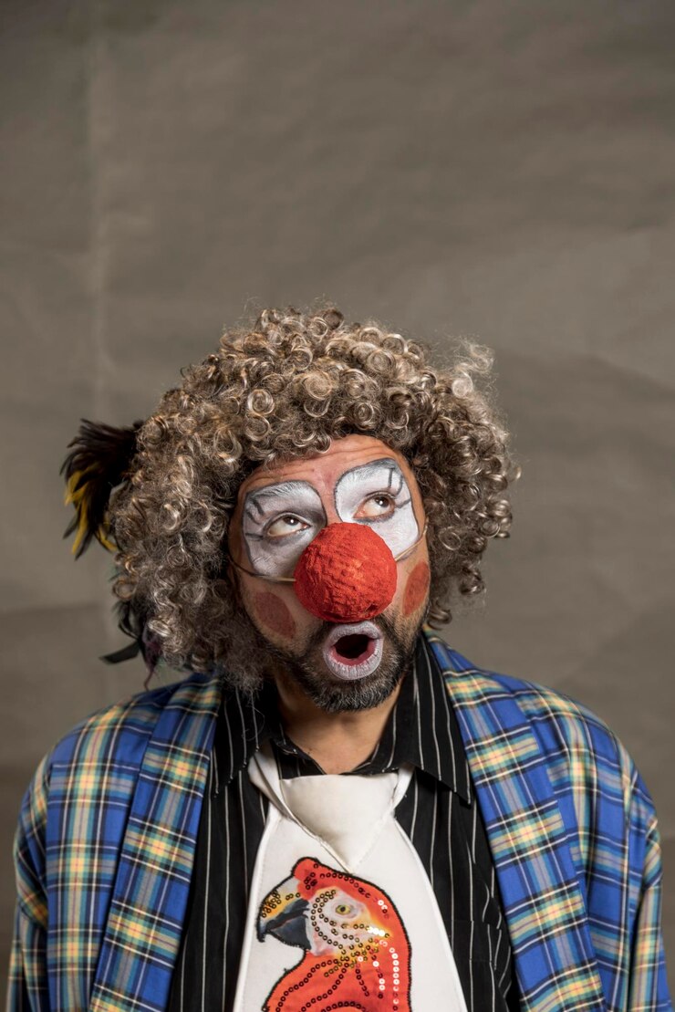 Foto um alegre palhaço de cabelos ondulados olha astutamente para cima retrato em close-up de perfil