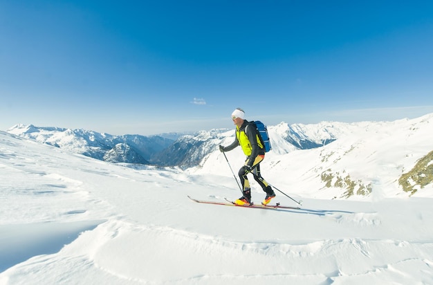 Um alpinista de esqui sozinho escala com peles de foca sob seus esquis