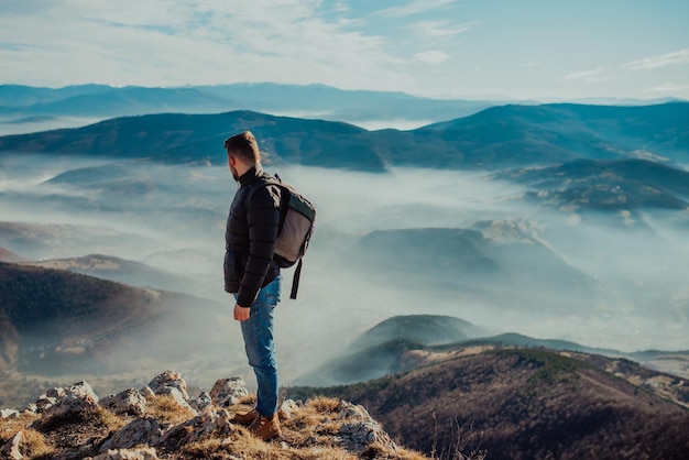 Um alpinista em uma jaqueta e com uma mochila no topo da montanha