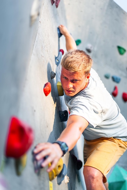 Um alpinista masculino está escalando ao ar livre em uma pedra artificial sem cinto de segurança