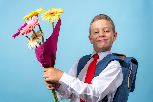 Um aluno de primeira classe com uma camisa branca e uma mochila segura um buquê de flores em suas mãos
