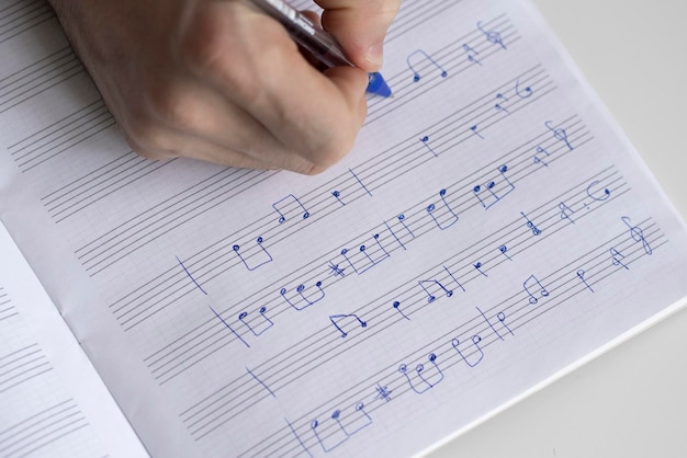 Um aluno na escola de música escreve notas musicais no caderno