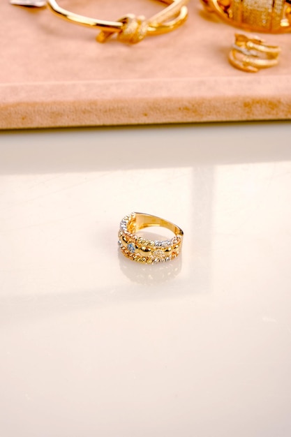 um anel de ouro com diamantes em cima dele senta-se em uma mesa