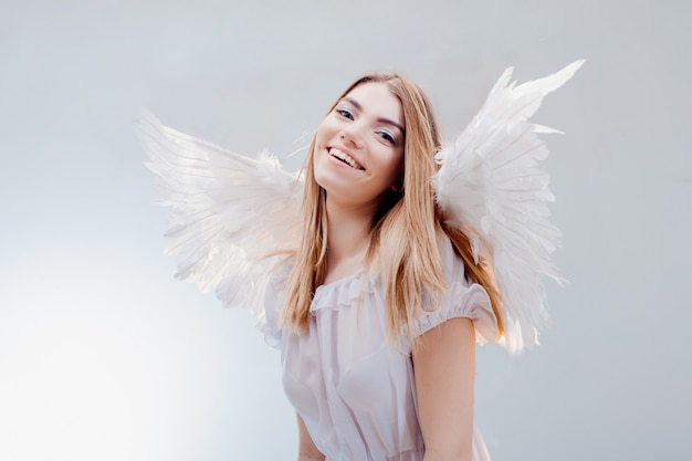 Foto um anjo do céu. jovem loira maravilhosa à imagem de um anjo com asas brancas.
