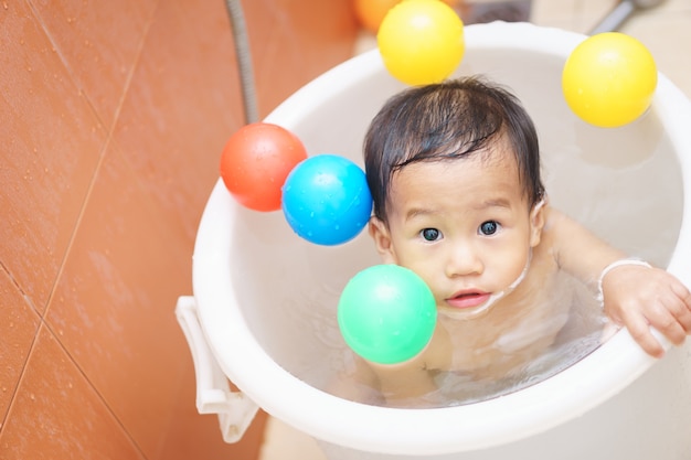 Um ano de idade e 5 meses bebê asiático jogar uma bola enquanto toma banho