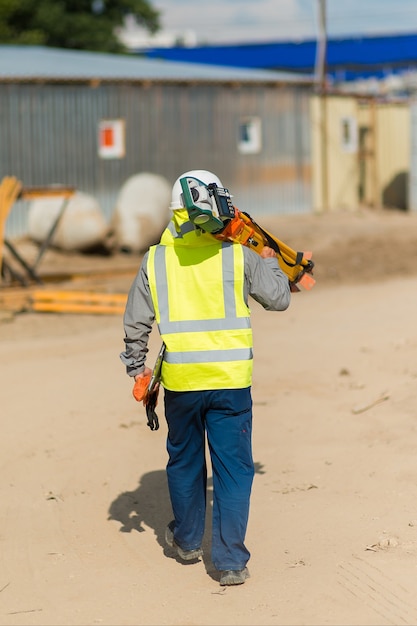 Um arquiteto com um nível de laser caminha ao longo do canteiro de obras, vista de trás