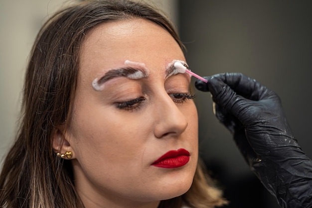 Um artista de sobrancelhas está laminando as sobrancelhas de uma linda cliente