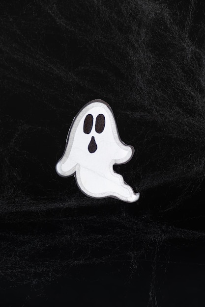 Um assustador fantasma branco voa em um fundo preto com uma teia um cartão postal de Halloween