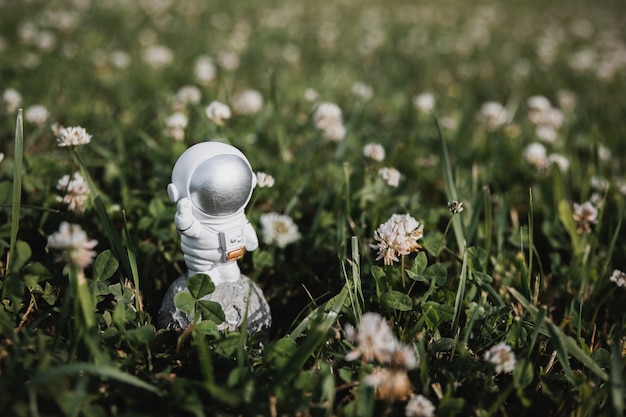 um astronauta de brinquedo fica parado na grama alta e acena com a mão