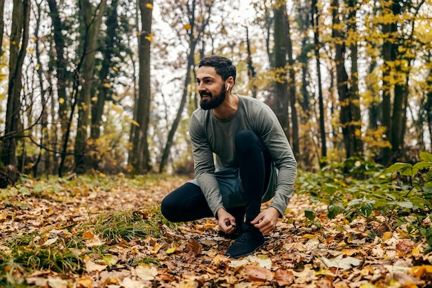 Foto um atleta feliz está amarrando seus atacadores na natureza e se preparando para correr