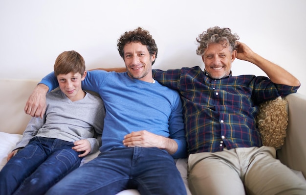 Um atrás do outro Retrato de três gerações de homens sentados em um sofá em casa