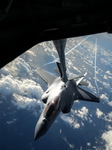 Um avião de combate está voando sobre as nuvens e o céu