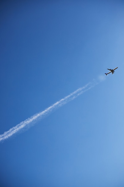 Um avião em um céu claro decola deixando uma linha