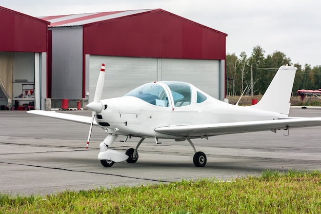 Um avião esportivo ao lado dos hangares