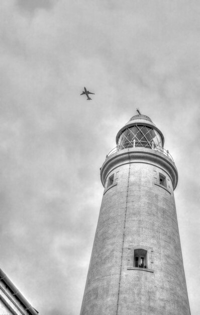 Foto um avião passa por cima de um farol.