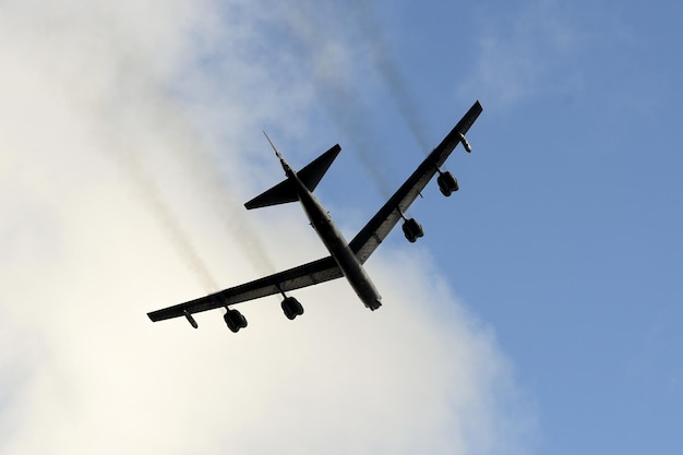 Um avião preto está voando pelo ar com fumaça saindo dele.