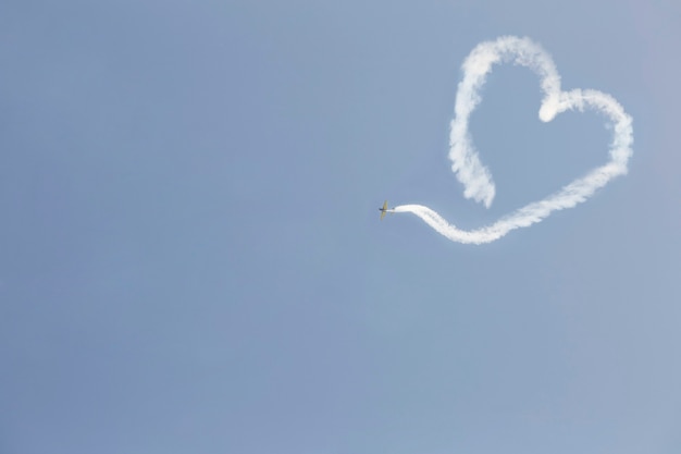 Um avião voando com fumaça em forma de coração. Dia dos Namorados.