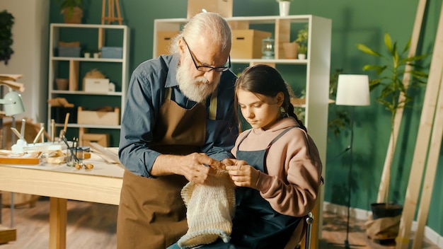 Um avô carinhoso ensina sua neta adolescente a tricotar na oficina