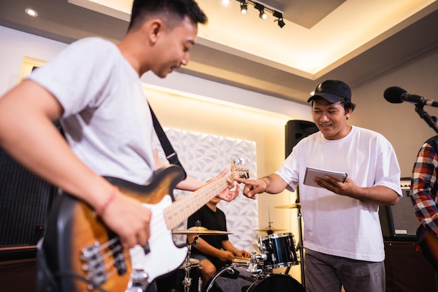 Um baixista toca baixo elétrico com um vocalista durante a afinação