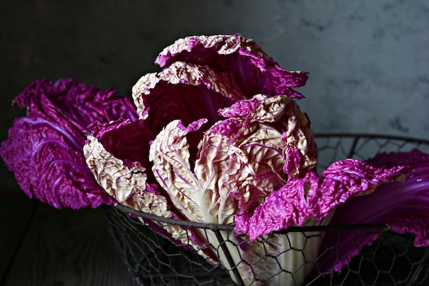 Um balanço de repolho roxo fresco muito peri chinês de Pequim em uma cesta em um fundo escuro de madeira