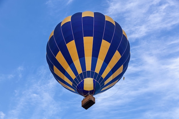 Um balão com uma cesta cheia de ar quente voa no céu azul Um balão de ar no céu azul