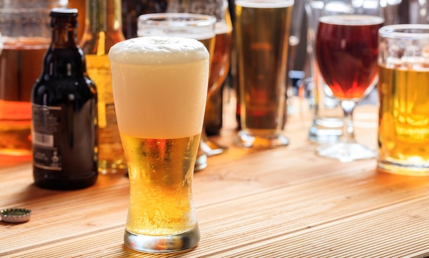 Um balcão de pub de madeira se concentra em um copo cheio de cerveja gelada