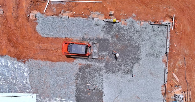 Um balde de escavação está em processo de nivelamento de cascalho para uma fundação de construção