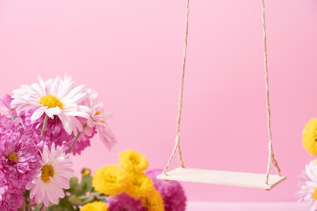 Um baloiço com flores de crisântemo como suporte para o seu produto cosmético