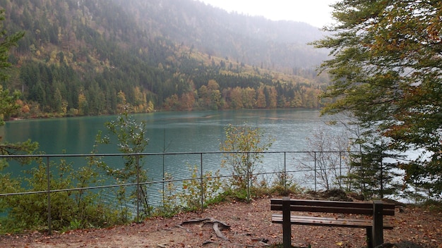 Um banco em frente a um lago com uma montanha ao fundo.