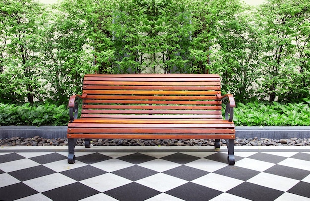 Um banco em um parque público em um dia de primavera ou verão um banco de madeira para relaxar plantado com árvores