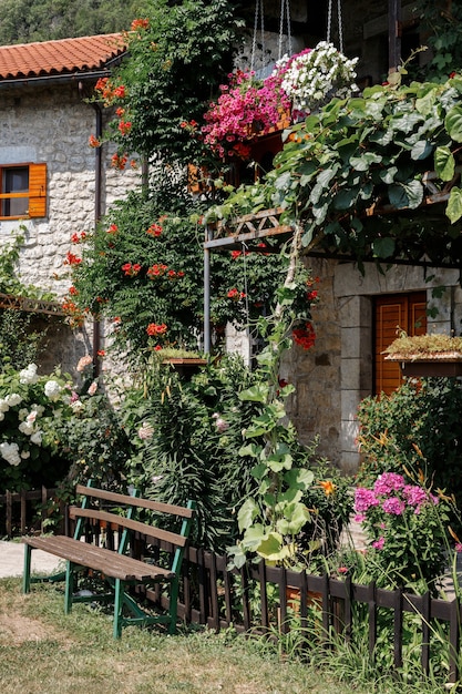 Um banco no jardim de verão perto de um edifício de pedra com telhado de telhas. clima de verão