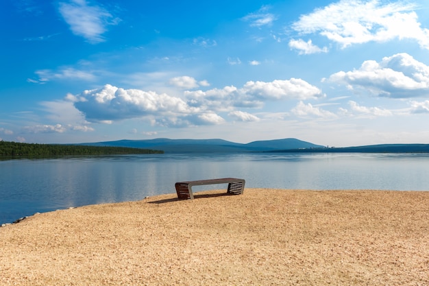 Foto um banco vazio na costa deserta. local para meditações, reflexão e introspecção. vista panorâmica incrível do lago e das montanhas.