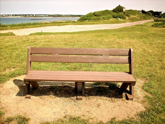 Foto um banco vazio num parque à beira-mar.