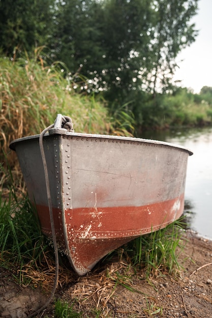 Um barco a motor está estacionado na margem de um lago ou rio à noite ao pôr do sol ou no início da manhã